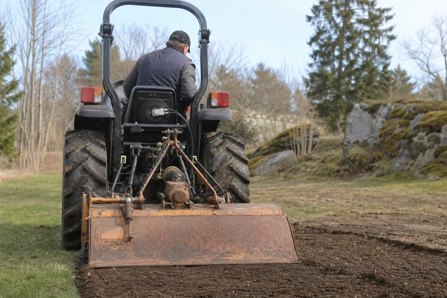 Traktor bakifrån med varumärkesfri fräs i trepunktslyften.